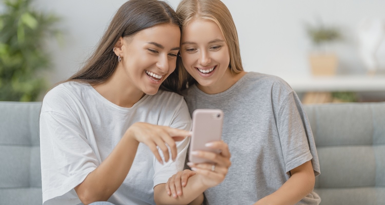 Two girls talking together enjoying fellowship looking at phone