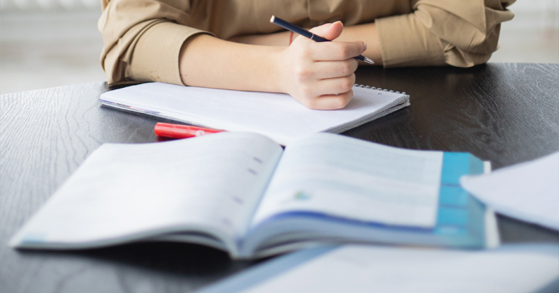 Woman studying with textbook open, writing